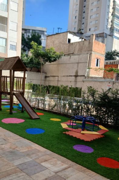 Playground do condomínio depois da reforma, com grama sintética e brinquedos